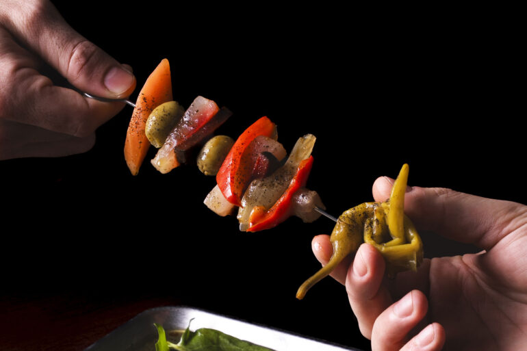 Pinchos con giardiniera fatta in casa, peperoni, olive spagnole, conditi con olio, soia e miele, menu Sapore